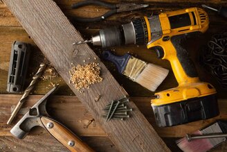 Tradesperson's tools: cordless drill, hammer, paintbrush and screws